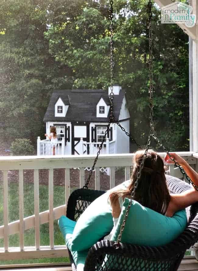 La femme est assise sur la balançoire du porche.